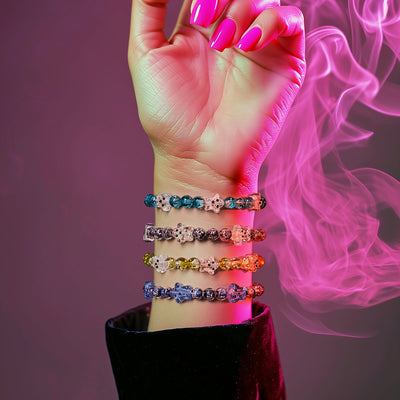 NOGU Monster Glow Mash beaded bracelets with colorful skull accents, styled on a wrist in neon pink Halloween lighting.