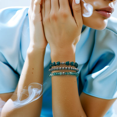 NOGU Arctic Mirage bracelets with teal gemstone beads and silvery metal accents, styled against soft blue satin.