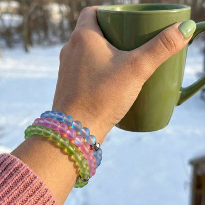 NOGU Made to Pair Sapphire Mermaid Glass bracelets in translucent ocean-blue, pink and green beads layered on a wrist.