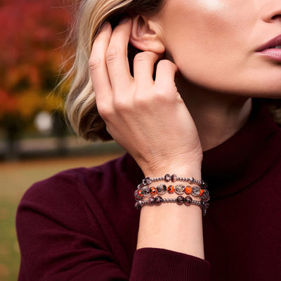 NOGU BOTM + Halloween bracelets stacked with dark metallic beads and orange Firefly Glass accents.