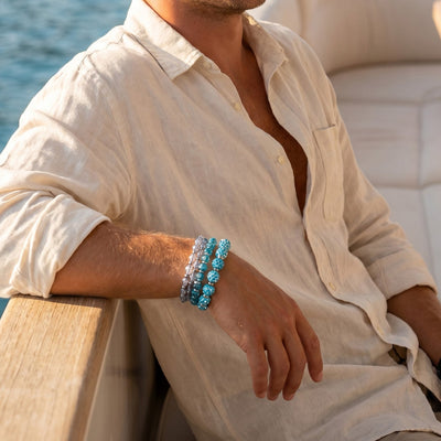 NOGU The Long Weekend Stack with shimmering turquoise and silver beaded bracelets styled on a man aboard a boat.