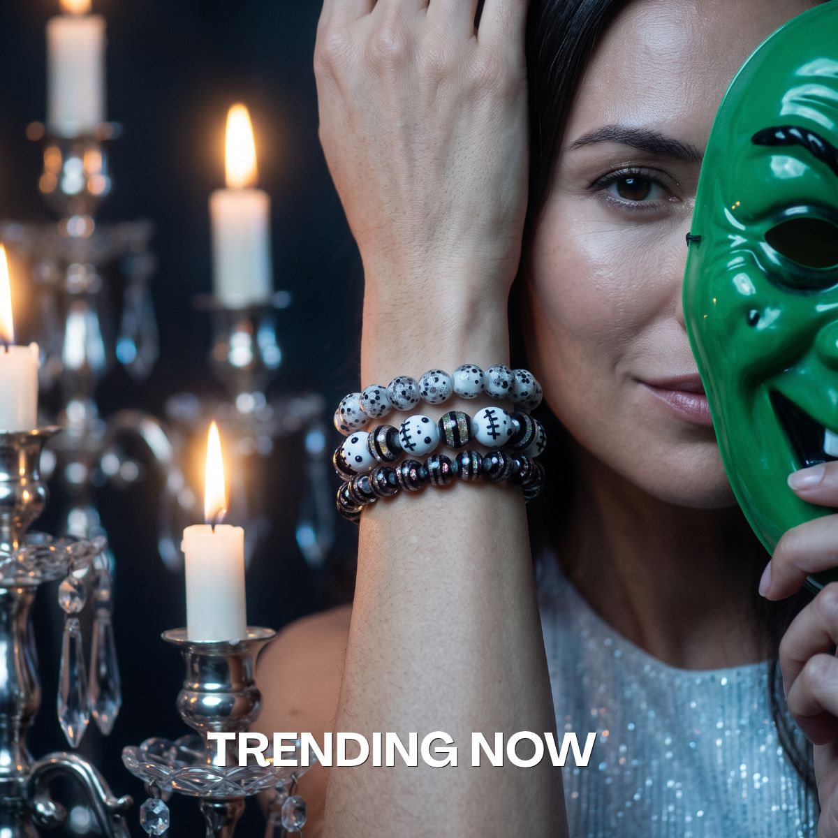 Woman wearing stacked black and white beaded bracelets with speckled and graphic-patterned beads beside a glossy green mask.