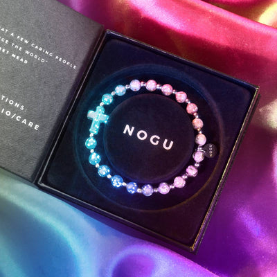 Periwinkle Firefly Glass Cross Bracelet glowing blue and purple beads in black NOGU box with silver accents