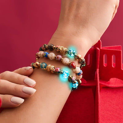 Shadow Dragon onyx Firefly glass and enamel lotus bead bracelet with gold-plated serpent charm on wrist by NOGU