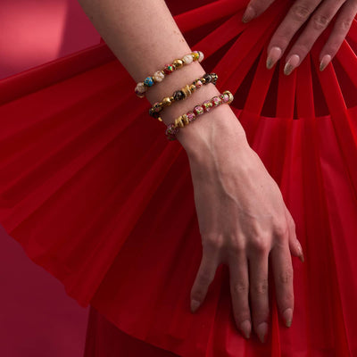 Shadow Dragon bracelet with enamel lotus, onyx Firefly glass beads, and gold-plated serpent charm worn on wrist by NOGU