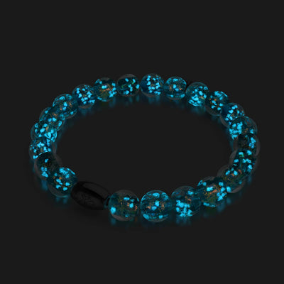 Aurora Spark bracelet with glowing teal Firework Glass beads and .925 sterling silver clasp glowing in darkness by NOGU