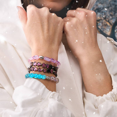 Midnight Borealis star wrap bracelet with pink and black star beads and silver logo charm worn with other beaded bracelets by NOGU