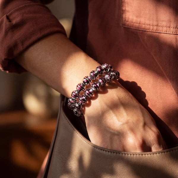 Atomic Fuchsia Firework Glass Orbit Bracelet with glossy black glass beads and bright fuchsia pink flecks, worn stacked on wrist.