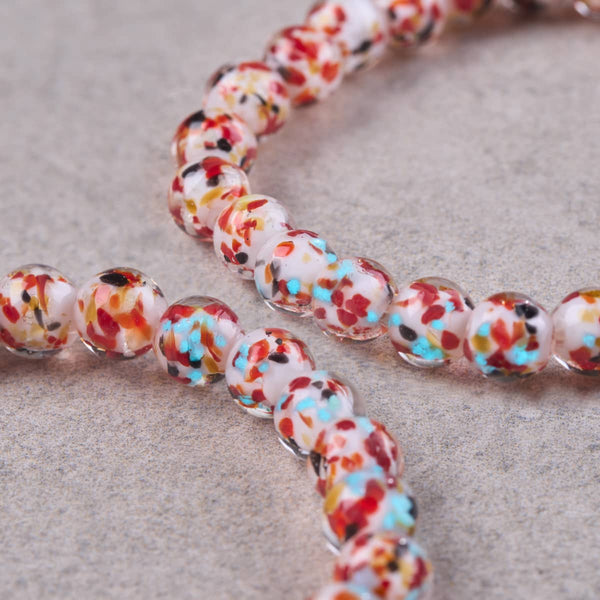 Florentine Fire terrazzo glass stretch bracelet with clear beads flecked in red, turquoise, black, yellow and white.