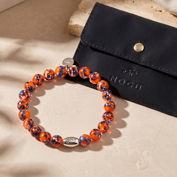 Glowing Ember sterling silver stretch bracelet with orange Firefly Glass beads flecked in blue and silver.