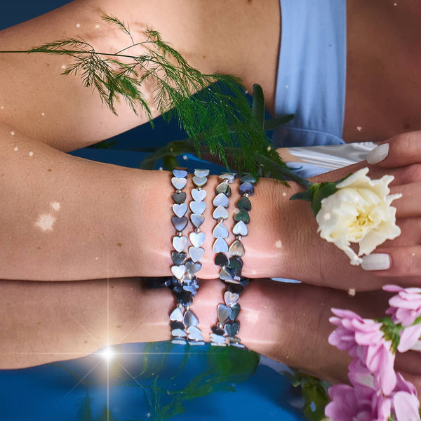 Black Mother of Pearl heart wrap bracelets with stretch cord and 18k white gold charms worn on wrist by NOGU