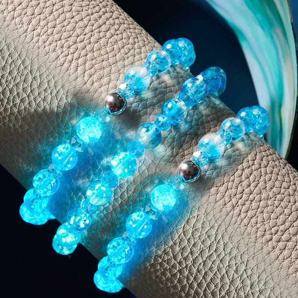 Aquamarine Ice Firefly Glass Snow Globe Bracelets glowing blue with faceted beads and silver accents on textured cushion by NOGU