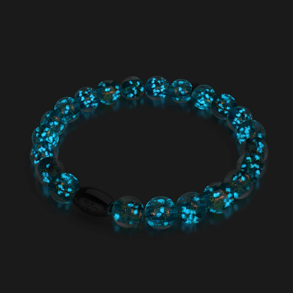 Aurora Spark bracelet with glowing teal Firework Glass beads and .925 sterling silver clasp glowing in darkness by NOGU