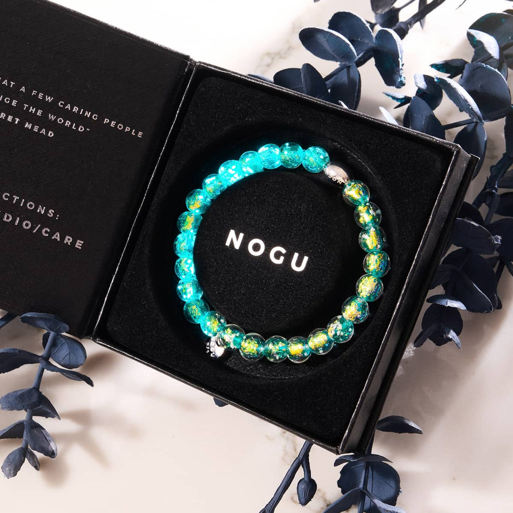 Aurora Spark bracelet with teal and gold Firework Glass beads in black box with NOGU logo and .925 sterling silver accents