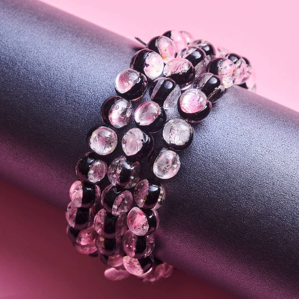 Pink Moon Lunar Glass bracelets with translucent pink and black beads displayed on a textured black stand by NOGU