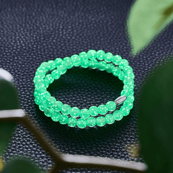 Cactus Firefly Glass wrap bracelet with glowing green 6mm beads and sterling silver clasp on black leather surface by NOGU