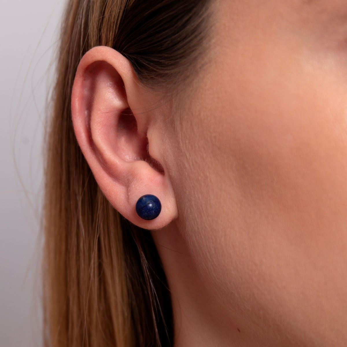 Close-up of deep blue lapis stud earrings, adding a touch of midnight magic.